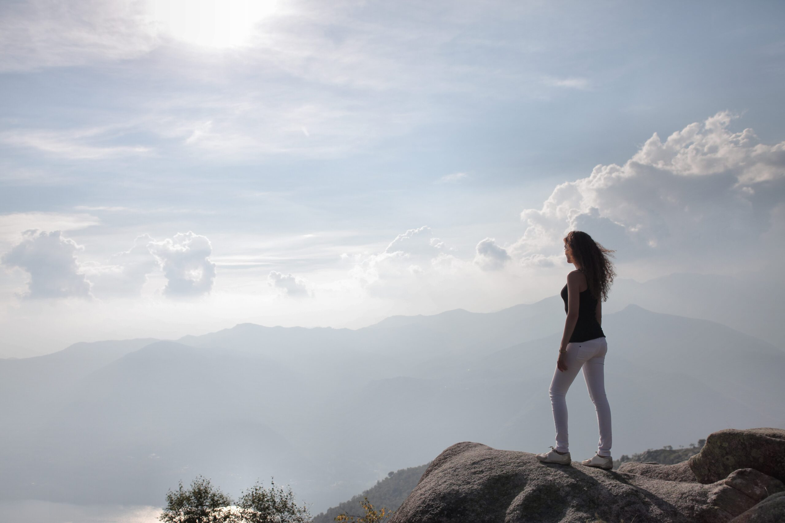 Woman on top of mountain looking out at sky