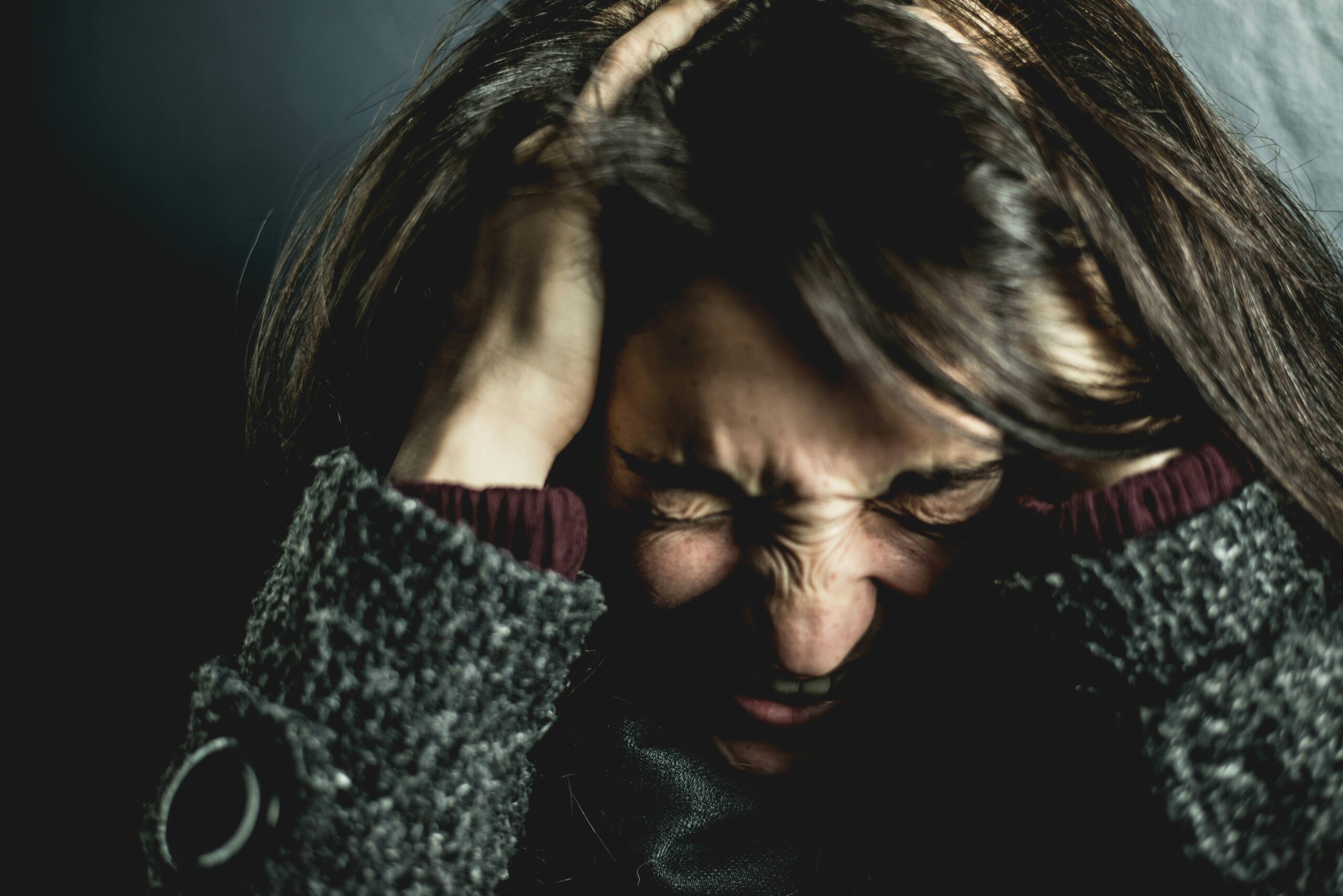 Stressed woman grabbing at her hair and scrunching her face in anger